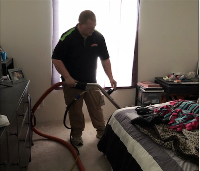 A SERVPRO crew member in action extracting water in the bedroom of a water damaged home.