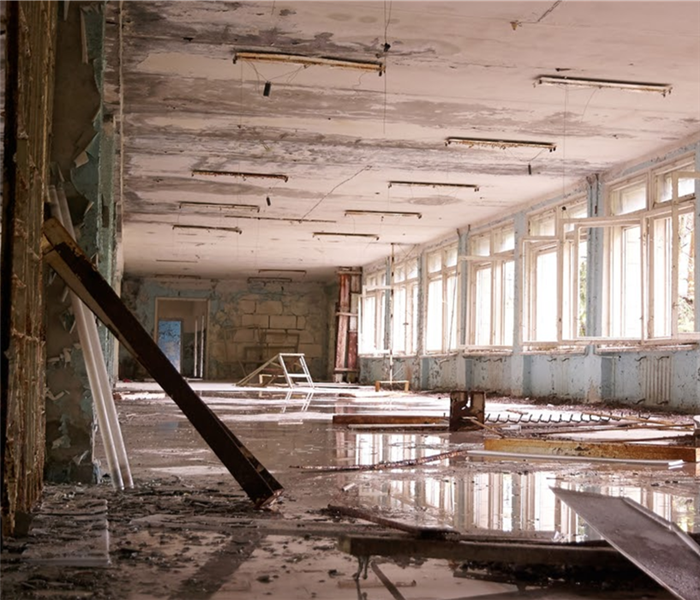 big abandoned hall with big broken windows, white on the floor and puddles
